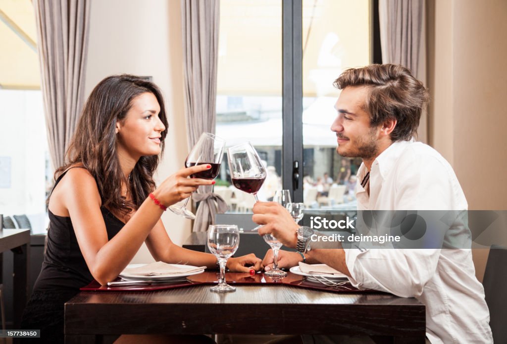 Jeune couple célébrer avec vin rouge au restaurant - Photo de Tous types de couple libre de droits