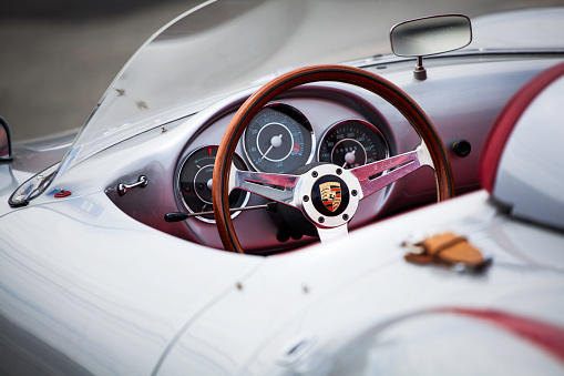 Halifax, Nova Scotia, Canada - June 16, 2012: At a public car gathering, a Porsche 550 Spyder replica interior. Focus on steering wheel with instrument panel and dash mounted rearview mirror visible inside the car. Asphaly surface visible in front of car and out of focus.  The 550 Spyder is one of the most replicated of classic automobiles with numerous companies creating almost exact replicas of the car.