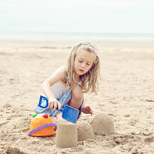 Sister and brothers and  having fun building a sandcastle on the beach.