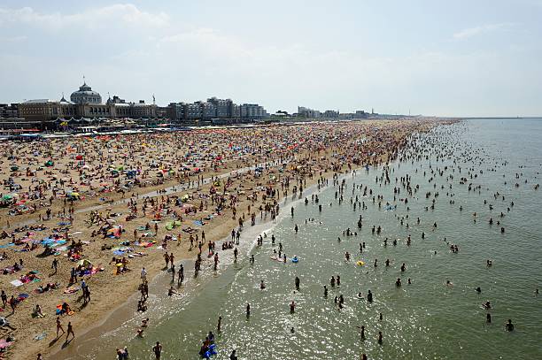 Scheveningen, Zuid-Holland / The Netherlands - June 9 2019: People enjoy themselves on the North Sea beach in Scheveningen with the boulevard in the background