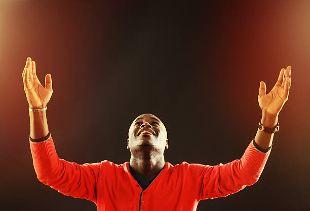 Inspired young man looks up, his hands raised in prayer