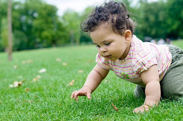 Royalty free stock photo of an 8 months old girl crawling on grass.