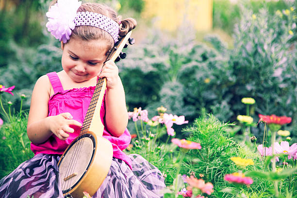 adorable petite fille jouant avec des fleurs vintage ukulélé banjo - formal garden ornamental garden child single flower photos et images de collection