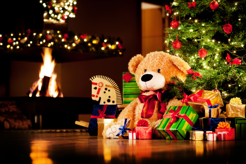 Christmas gifts under christmas tree with fireplace in background.