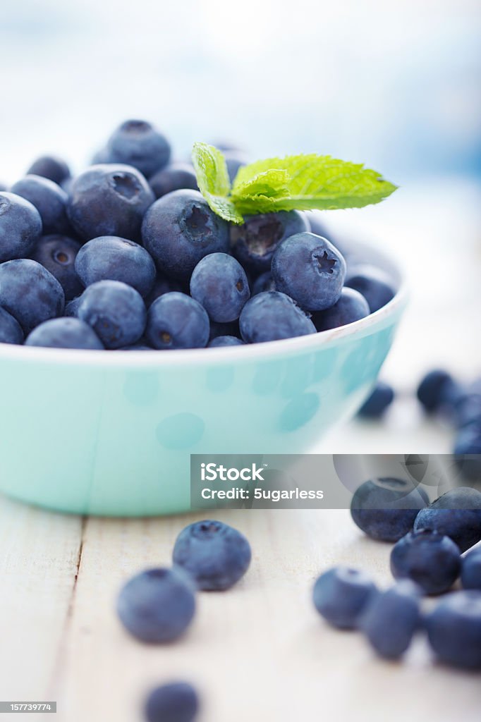 A blue bowl overfilled with blueberries Blueberries in a bowl with leafs of mint Blueberry Stock Photo