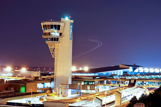 Airport Control Tower in dusk Airplane is taking off behind the control tower remaining the its flying trak in dusk. air traffic control tower stock pictures, royalty-free photos & images