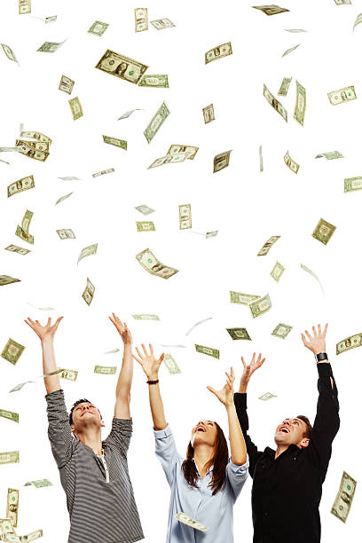 Three overjoyed young adults being showered with dollars Three smiling young adults with arms raised try to catch the many dollars raining down on them. Isolated on white. pennies from heaven stock pictures, royalty-free photos & images