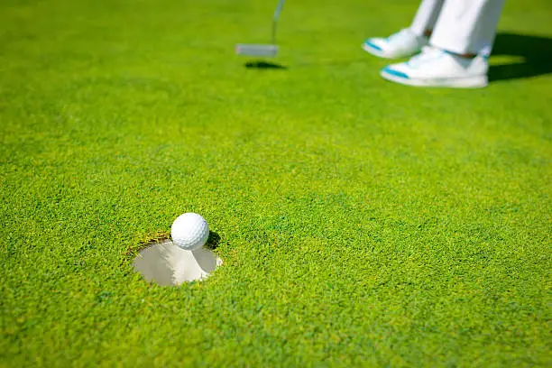 Golfer Putting Golf Ball In The Hole
