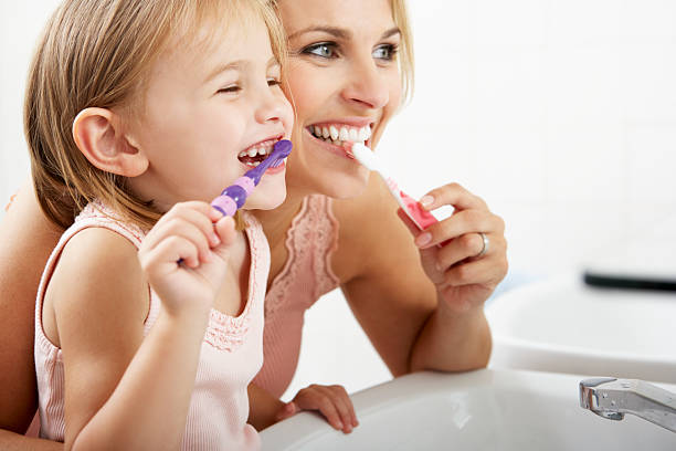 Mother And Daughter Brushing Teeth Together Mother And Daughter Brushing Teeth Together Over Sink oral care in kids stock pictures, royalty-free photos & images