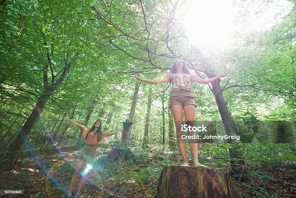 Nature Worship Three young friends with arms outstretched enjoying the sun rays in woods. Forest Stock Photo