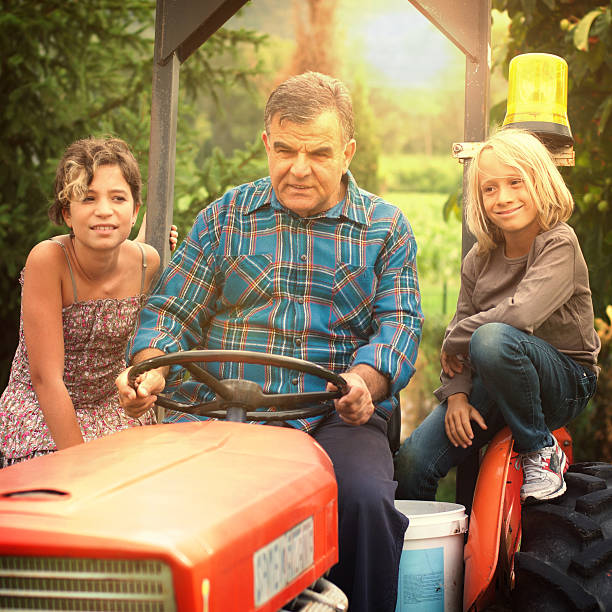 agricoltore e i suoi nipoti su un trattore - casual granddaughter farmer expressing positivity foto e immagini stock