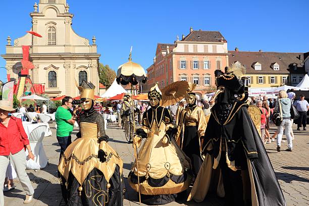 Ludwigsburg, Germany - September 8, 2012: A scene of the Venezianische Messe (Venetian Fair), a carnival event in honour of the Venetian Carnival in Italy. You can see colorful dressed people with carnival costume in gold-black colors in front of the church on the marketplace in Ludwigsburg/Germany.