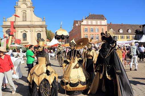 Ludwigsburg, Germany - September 8, 2012: A scene of the Venezianische Messe (Venetian Fair), a carnival event in honour of the Venetian Carnival in Italy. You can see colorful dressed people with carnival costume in gold-black colors in front of the church on the marketplace in Ludwigsburg/Germany.