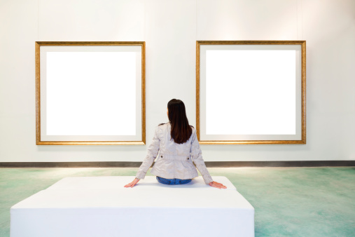 One woman looking at white frame in an art gallery