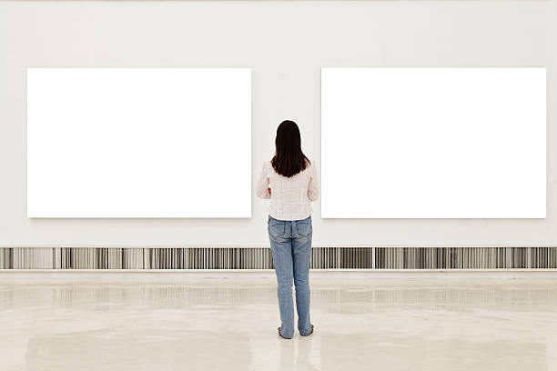 A woman in an art gallery looking at white frames