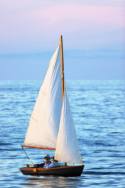 senior pareja navegando sloop puesta de sol - rowboat dinghy nautical vessel nautical equipment fotografías e imágenes de stock