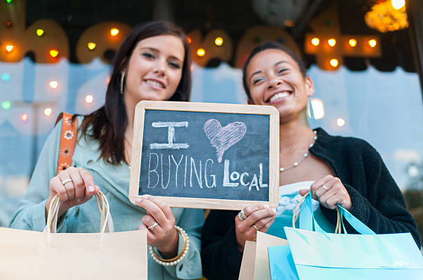 Two women holding up sign for buying local stock photo