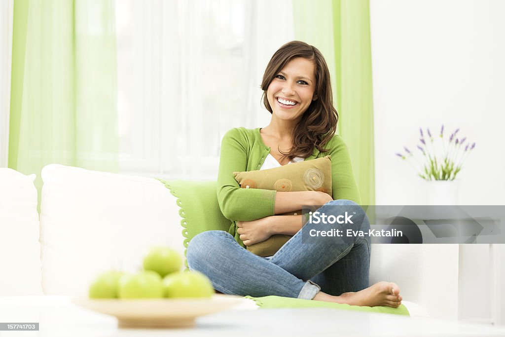 Mulher sorridente, sentado tranquilamente no sofá em casa - Foto de stock de Mulheres royalty-free