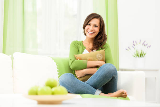 mulher sorridente, sentado tranquilamente no sofá em casa - granny smith apple apple food fruit - fotografias e filmes do acervo