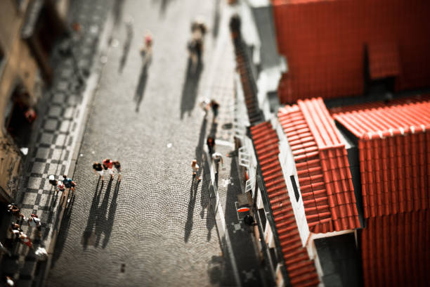 Aerial view of people walking on a cobblestone alley in Prague at sunset. Tilt shift lens.