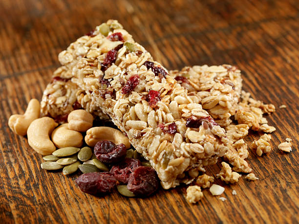 Granola Bars Granola Bars with Mixed Nuts and Cranberries on an Old Wood Table -Photographed on Hasselblad H3D2-39mb Camera chewy stock pictures, royalty-free photos & images