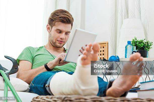 Young Man With Broken Leg At Home Stock Photo - Download Image Now - Orthopedic Cast, Broken Leg, Home Interior