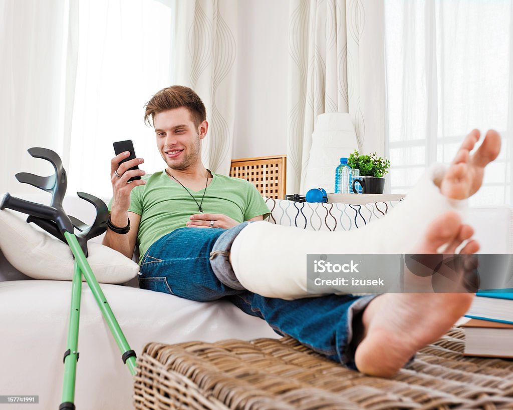 Jeune homme avec une jambe cassée à la - Photo de Jambe cassée libre de droits