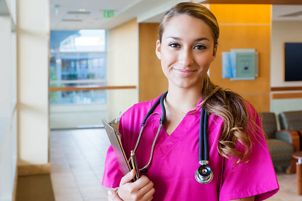 Young Hispanic Nurse in Pink Scrubs with Clipboard stock photo