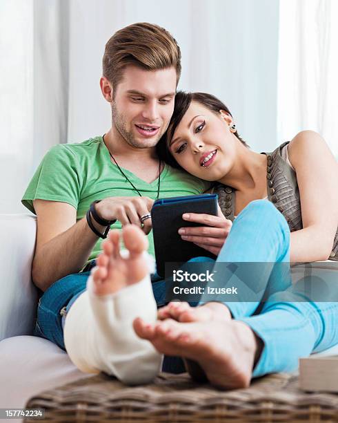 Young Couple Using Ereader Stock Photo - Download Image Now - Happiness, Bone Fracture, Orthopedic Cast