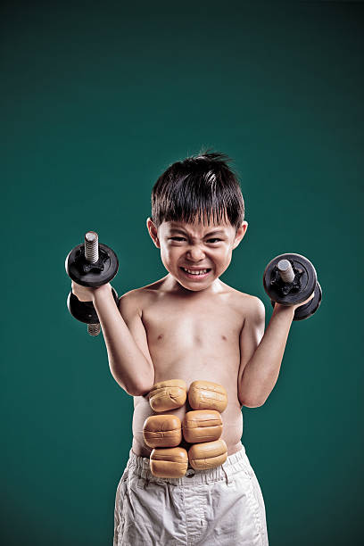маленький мальчик imagines он содержит силу мышц. - flexing muscles little boys human muscle strength стоковые фото и изображения