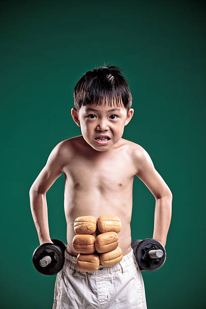 маленький мальчик imagines он содержит силу мышц. - flexing muscles little boys human muscle strength стоковые фото и изображения