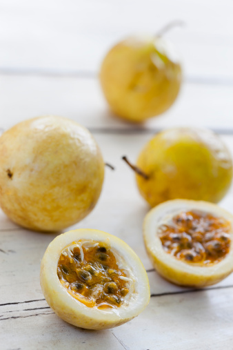 Cross section of a Passion fruit amongst un-cut fruit on an old wooden board table. Selective focus.