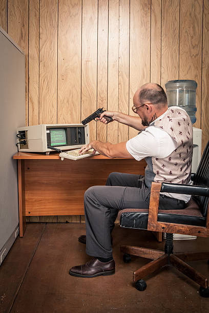 enraged bureau de travail visant une arme à feu sur old ordinateur cassé - computer shooting handgun gun photos et images de collection