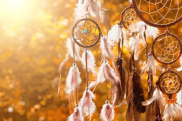 dreamcatcher detail in the evening in front of blurry trees. Indian Summer. 