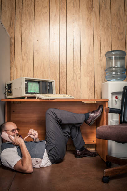 istock retro office worker hiding under desk while on the phone 157742996