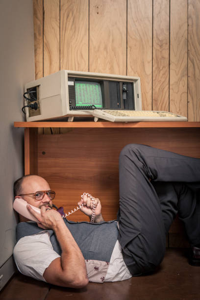 istock 1980's office worker hiding under desk while on the phone 157743061