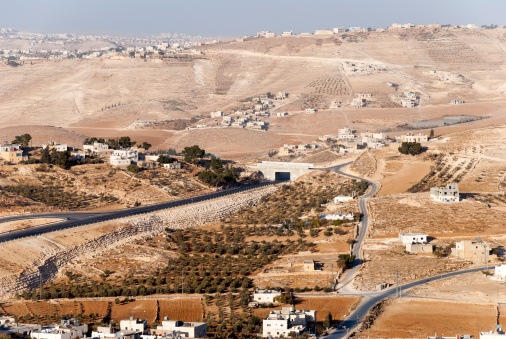 View of Palestinian homes, fields, and communities outside the West Bank town of Bethlehem. On the hill in the far left of the image are the red tiled roofs of Jewish settlements.