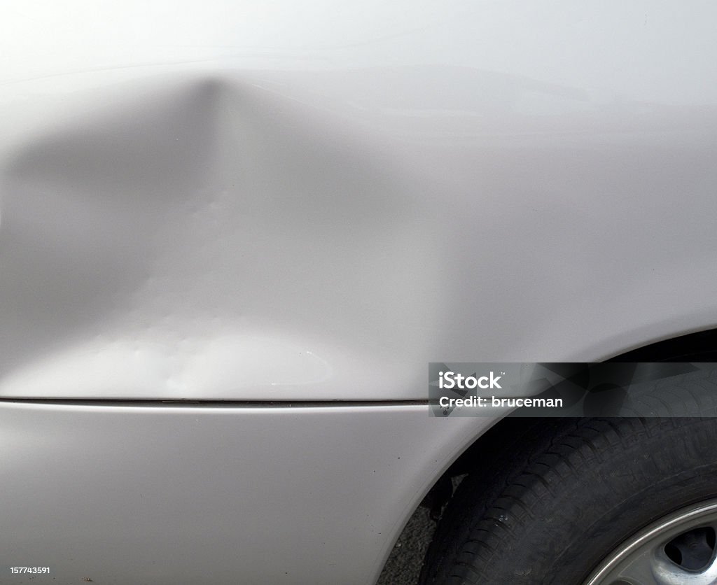 Close-up of a dent in a gray car exterior Crumpled fender on car after an auto accident. Dented Stock Photo