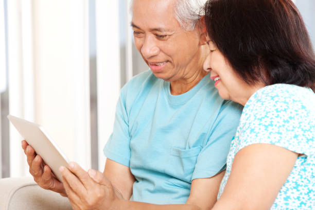 istock Happy Senior Asian Couple Having fun with Tablet 157743616