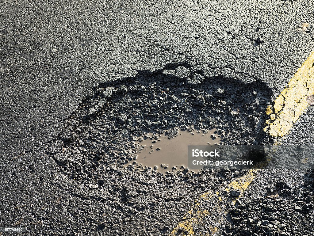 Dangerous Pot Hole on the Road Close-up of the effects of road weathering and neglect - a deep pot hole causing a danger to drivers. Pot Hole Stock Photo