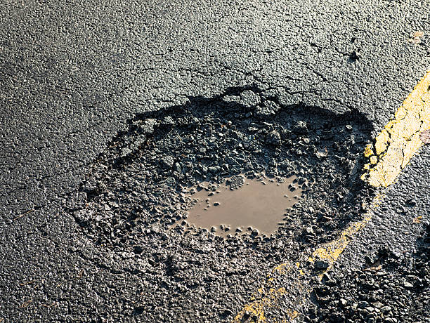 perigoso buraco de estrada na estrada - asphalt country road dividing line road marking - fotografias e filmes do acervo