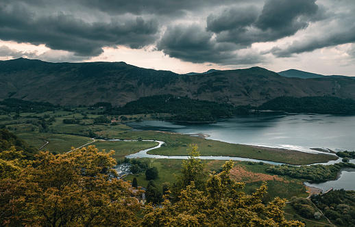 The scene of a curved stream flowing to the Derwent Water Lake in Lake district in overcast days