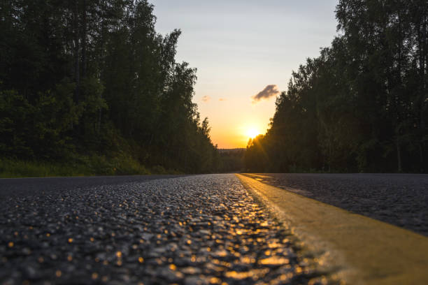 la línea amarilla de señalización vial está iluminada por el brillante sol poniente en grandes - 6721 fotografías e imágenes de stock