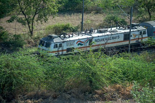 Pune, India - May 14 2023: Passenger Train hauled by a WAP7 loco heads towards Pune, at Kedgaon near Pune India.