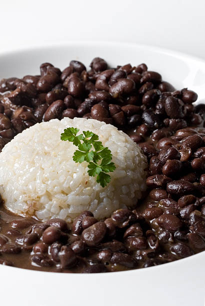 Rice and beans white rice accompanieded by black dry beans served in a plate with parsley decoration. vertical composition beans and rice stock pictures, royalty-free photos & images