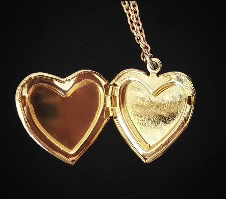 A gold heart-shaped locket against a black background