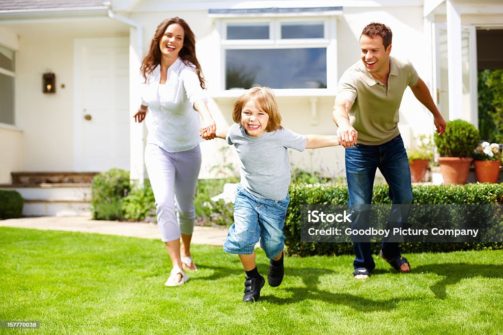 Divertido niño pequeño con sus padres divirtiéndose en hierba - Foto de stock de Familia libre de derechos