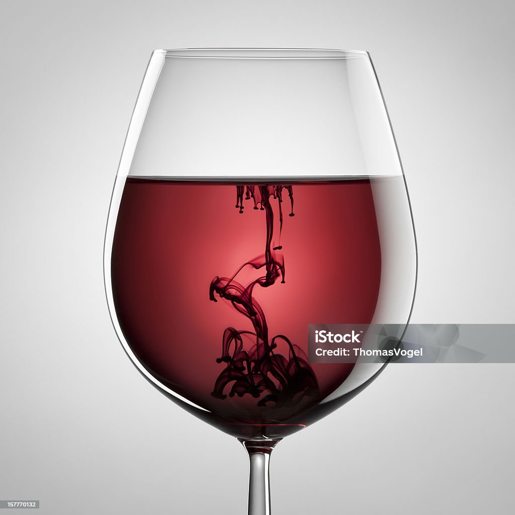 Wineglass, red wine and black ink. Abstract art Photograph of a wineglass filled with red wine and spreading black ink. Wine Stock Photo