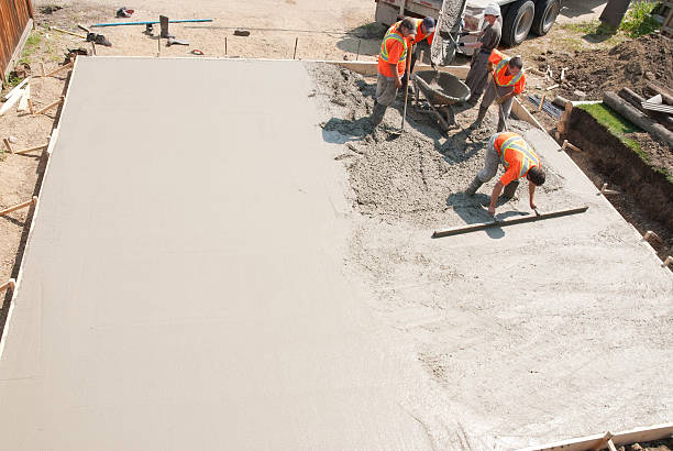 Concrete Crew Crew of concrete workers pouring and leveling a garage pad. Half of the pad is done and would make great copy space. driveway stock pictures, royalty-free photos & images