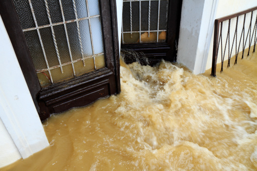 Dirty water is pouring out from the house entrance door in the catastrophic floods.